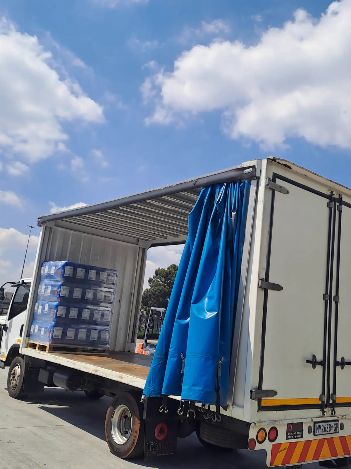Back of an MDL Logistics truck with the curtain side open and a stack of pallets secured on the deck